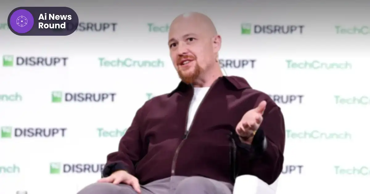 Replit CEO Amjad Masad speaking on stage at TechCrunch Disrupt, with the Ai News Round logo top left